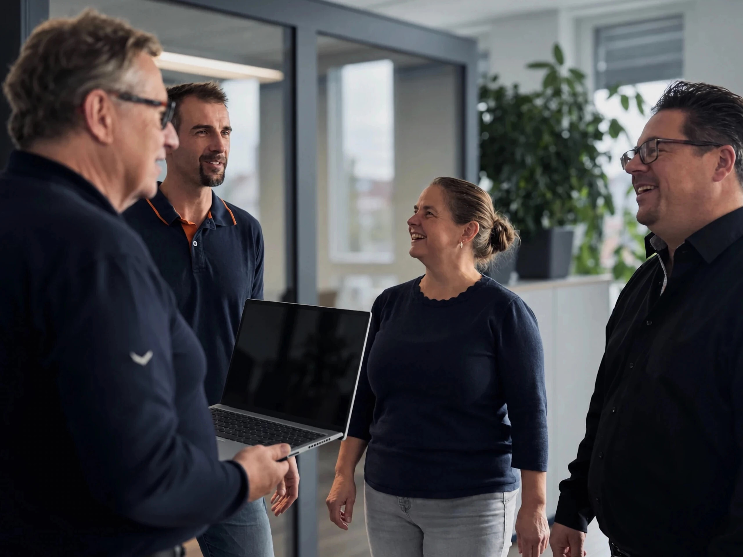 Team von Warnow Design im Gespräch im Büro, einer hält einen Laptop