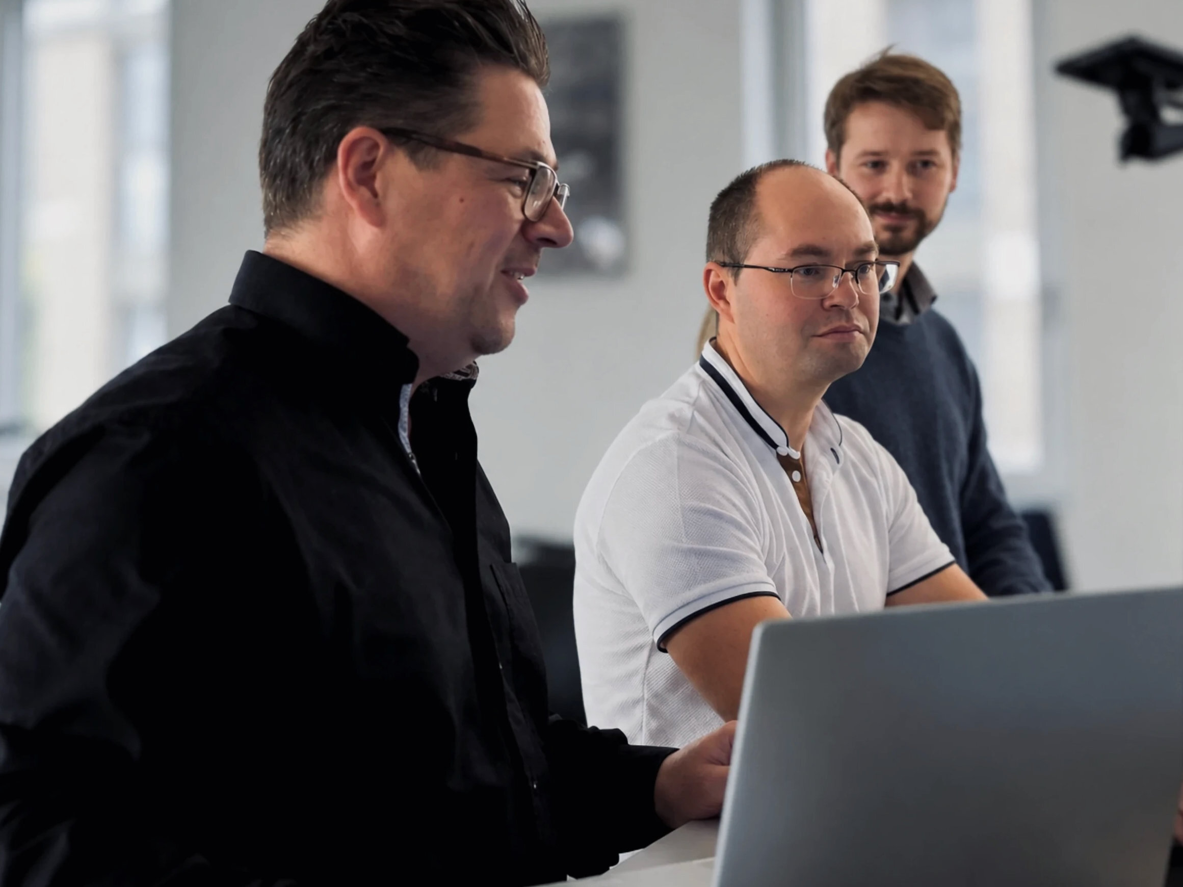 Three Warnow Design engineers talking at a laptop