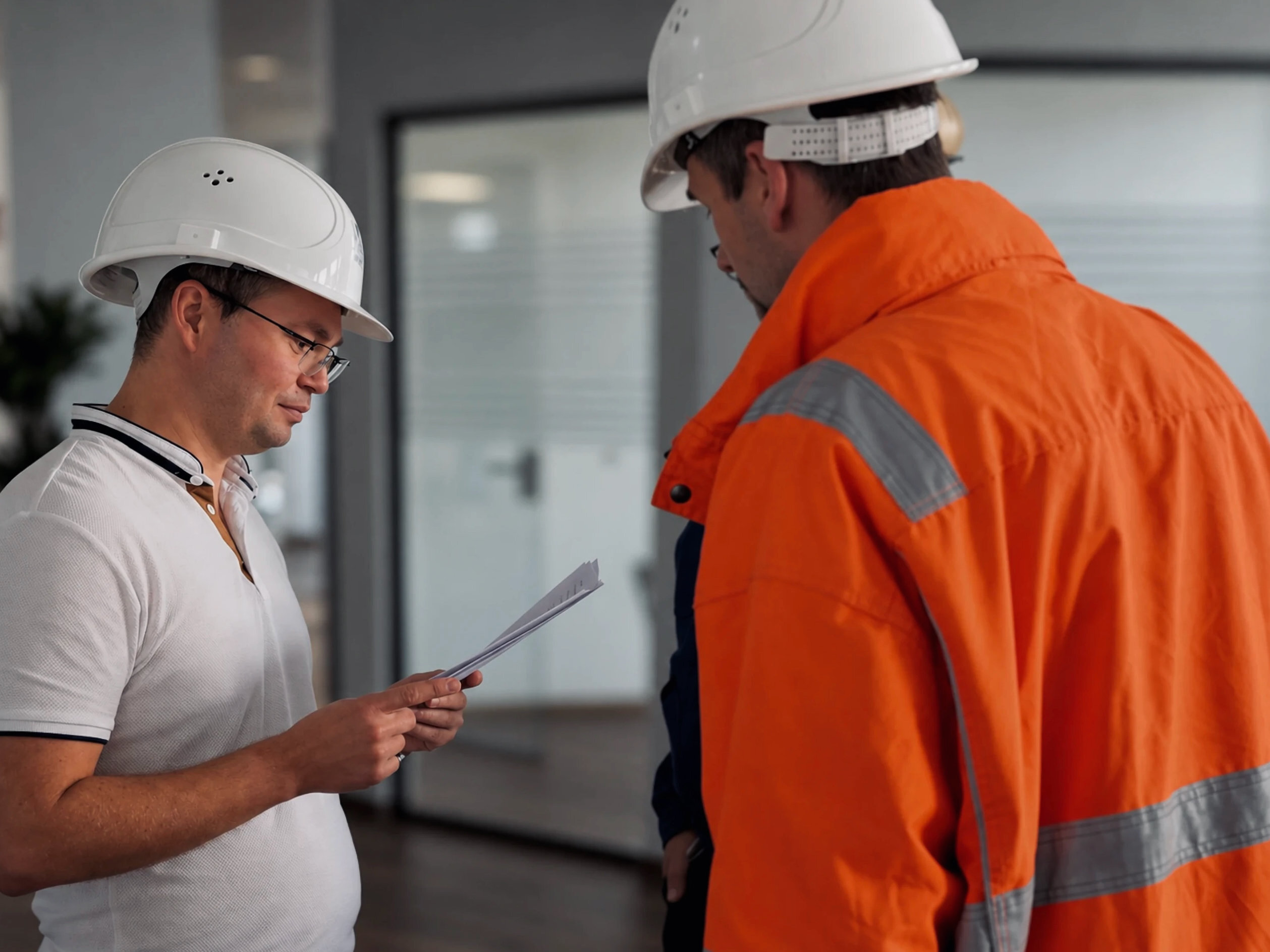 Engineers in hard hats and a high-visibility jacket checking documents