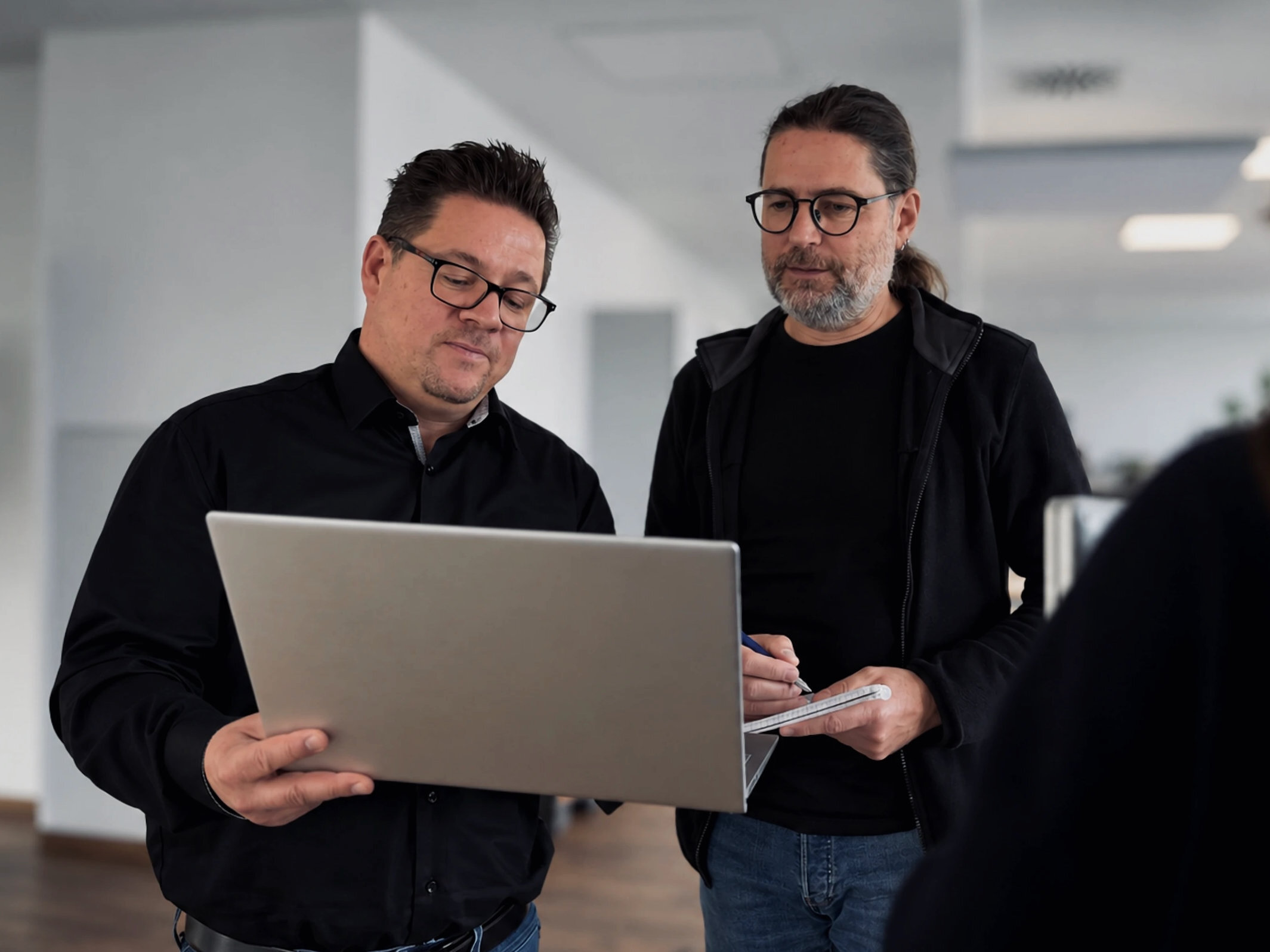 Two Warnow Design team members discussing something on a laptop in the hallway